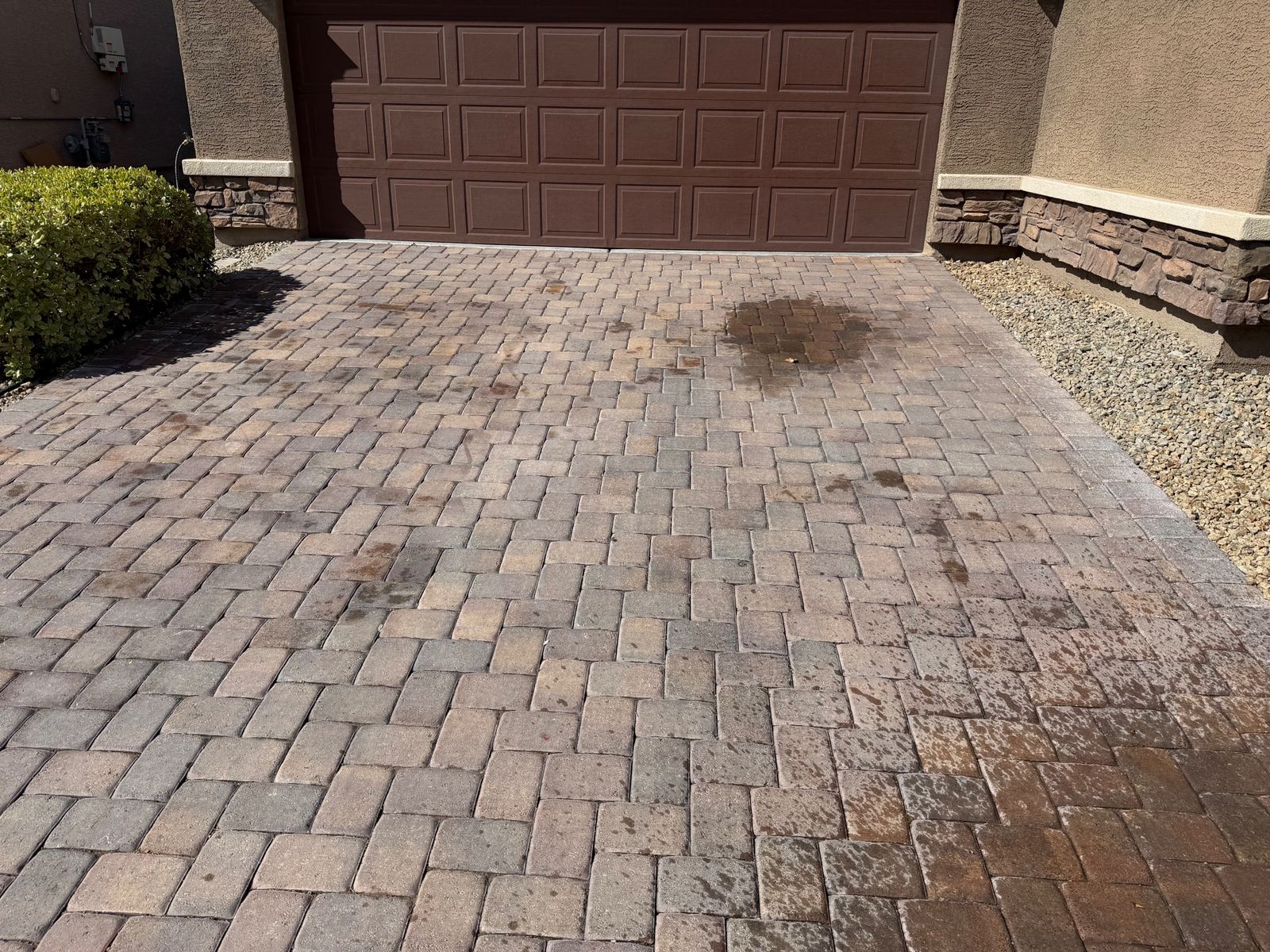 Paver driveway with a large oil stain and faded color