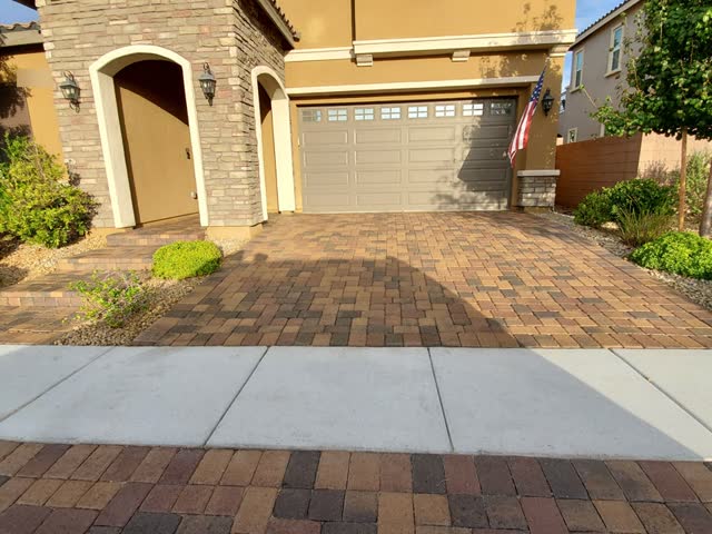 Paver driveway and entry steps at a stone-arched home