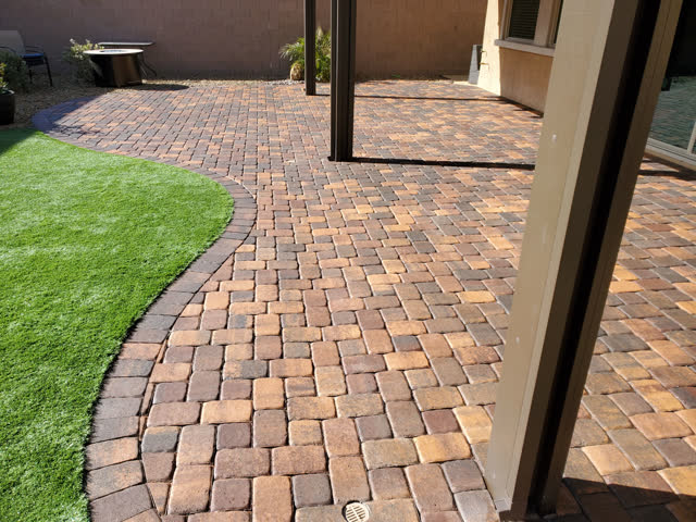 Curved paver patio beside artificial turf